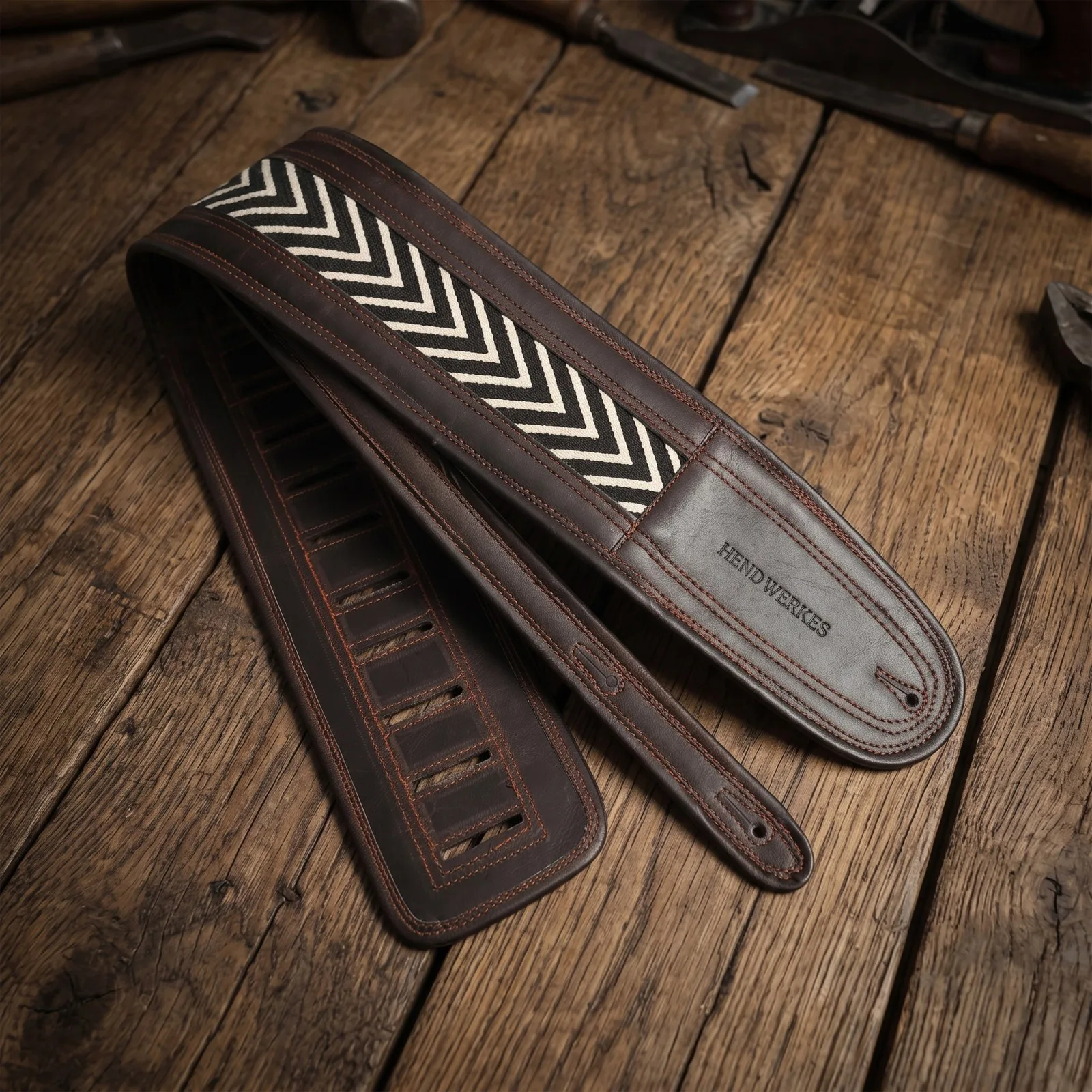 Chevron weave leather guitar strap on a woodworker’s bench